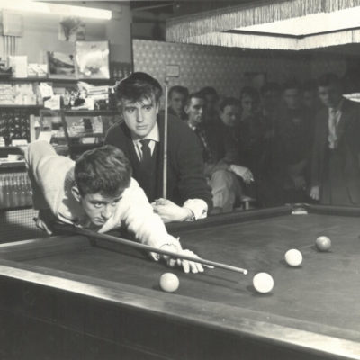 Gareth looks on as his competitor Roger Hart lines up a shot at the Under 18 snooker championship, Castle Snooker Club, Honey Lane, 1960.